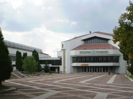 The chitalishte in Byala Slatina, a white building with a red roof behind a paved square